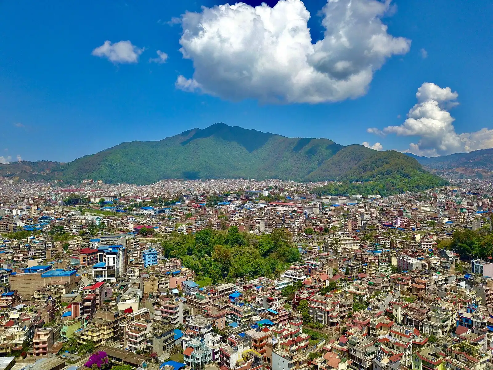 Aerial view of dense housing in Kathmandu with green hills behind