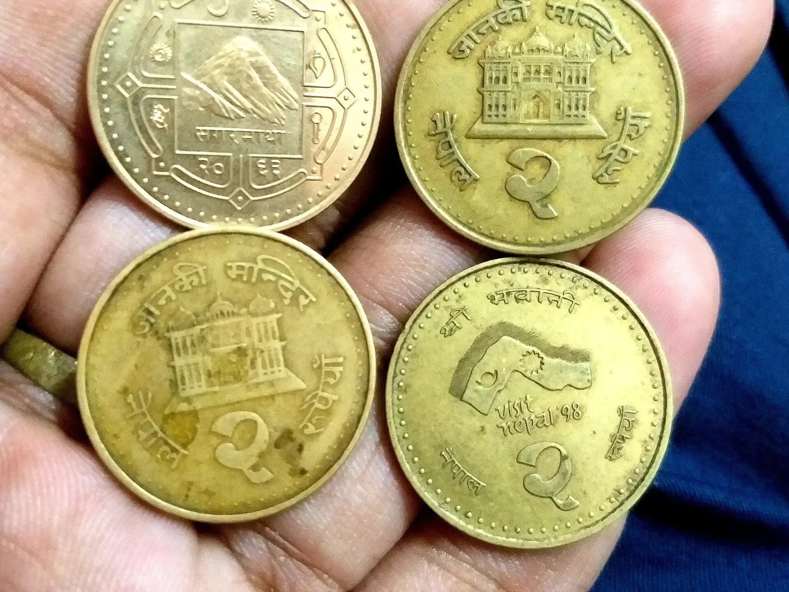 A hand holding Nepali two-rupee coins