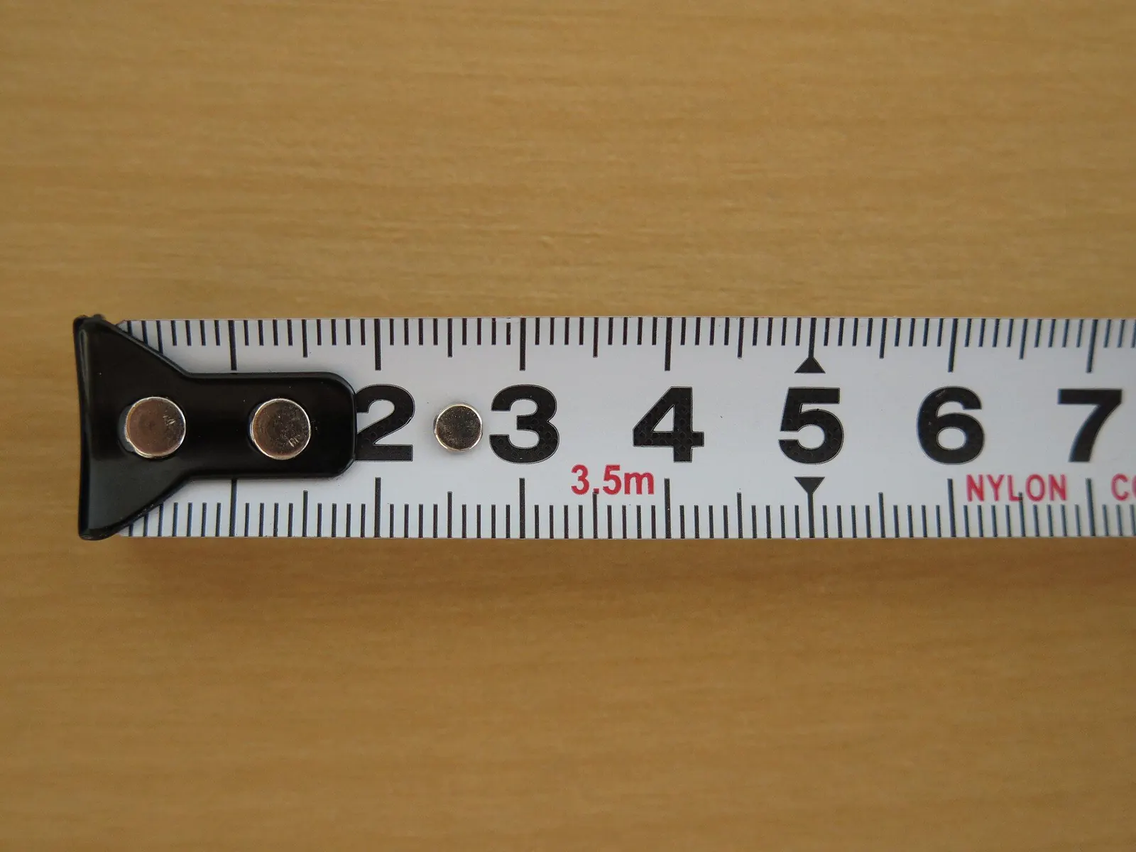 The end of a metal tape measure showing the first few centimetres